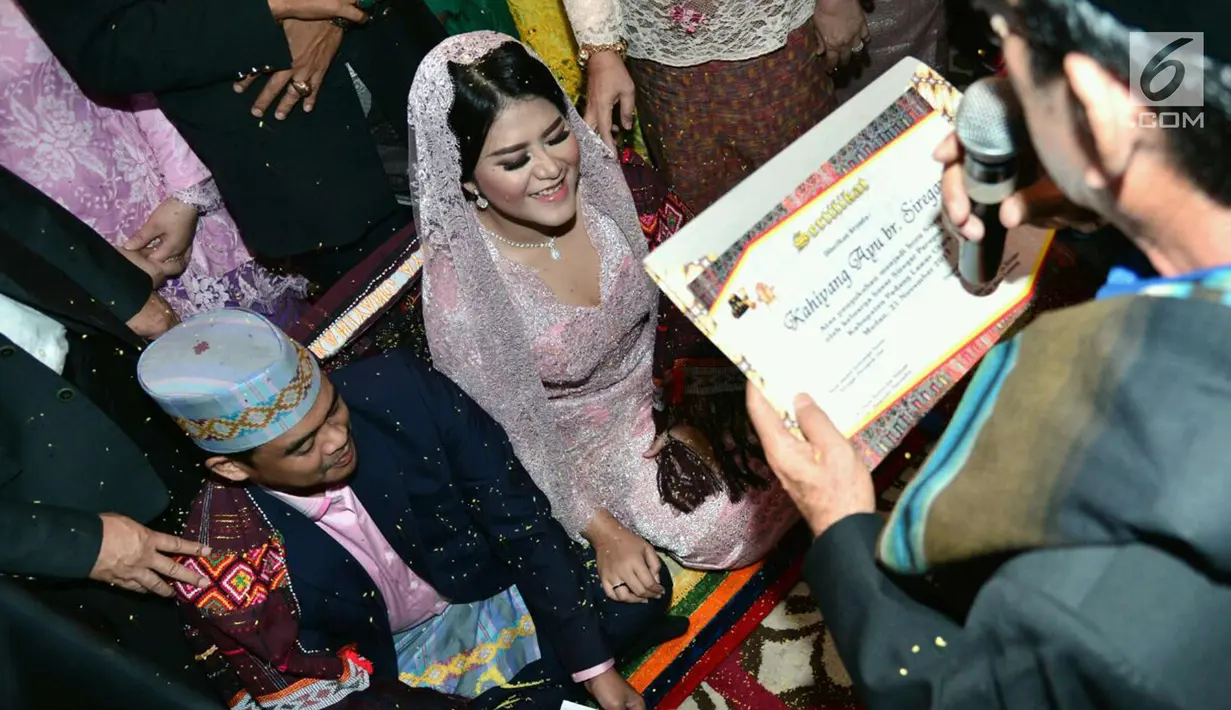 Putri Presiden Joko Widodo, Kahiyang Ayu dan Muhammad Bobby Afif Nasution menerima sertifikat  dalam prosesi Mangalehan Marga, Boru Siregar, di rumah paman Bobby di Medan, Selasa (21/11). (Liputan6.com/Pool/Media Center)