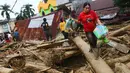 Orang-orang berjalan di atas puing-puing di daerah yang terkena banjir bandang di Masamba, Sulawesi Selatan, Rabu (15/7/2020). Banjir bandang yang terjadi akibat tingginya curah hujan itu mengakibatkan 16 orang meninggal dunia, sementara ratusan rumah rusak berat dan hilang. (AP/Khaizuran Muchtamir)