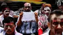 Seorang peserta aksi menunjukan poster selama menggelar demo di depan gedung Pertamina, Jakarta, Senin (23/10). (Liputan6.com/Angga Yuniar)