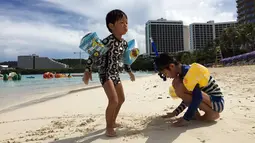Anak-anak bermain pasir di pantai Tumon, Guam, Kamis (10/8). Meskipun suasana ketegangan di kawasan itu meningkat terkait ancaman bom nuklir Korea Utara, warga Guam tetap beraktivitas seperti biasa. (AP Photo/Tassanee Vejpongsa)