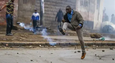Seorang pria menendang granat gas air mata ke arah polisi selama protes di ibu kota Nairobi, Kenya Jumat (7/7/2023). Lusinan pengunjuk rasa anti-pemerintah ditangkap di Nairobi karena bagian lain negara itu juga menyaksikan demonstrasi yang diserukan oleh oposisi terhadap pajak yang baru dikenakan dan biaya hidup. (AP Photo/Brian Inganga)