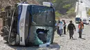 Petugas berdiri di dekat bus yang terbalik di jalan raya Caracas-La Guaira di Caracas, Venezuela, Rabu (10/2). Bus yang mengangkut pemain tim sepak bola Argentina Huracan itu kecelakaan saat menuju Bandara Internasional Simon Bolivar. (AFP/FEDERICO PARRA)