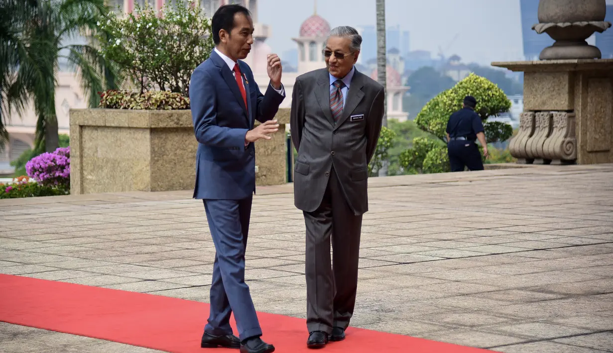 Presiden Joko Widodo berbincang dengan Perdana Menteri Malaysia Mahathir Mohamad usai upacara penyambutan resmi di Putrajaya (8/8/2019). Pertemuan membahas sejumlah isu dan upaya peningkatan kerja sama antara Indonesia dan Malaysia. (Farhan Abdullah/Department Of Information/AFP)