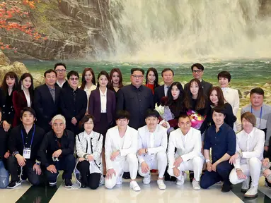 Pemimpin Korea Utara Kim Jong-Un (tengah) dan istrinya Ri Sol-Ju (tengah kiri) berfoto bersama sejumlah bintang K-pop dan musisi dari Korea Selatan di East Pyongyang Grand Theatre, Korea Utara (4/1). (AFP Photo/KCNA)