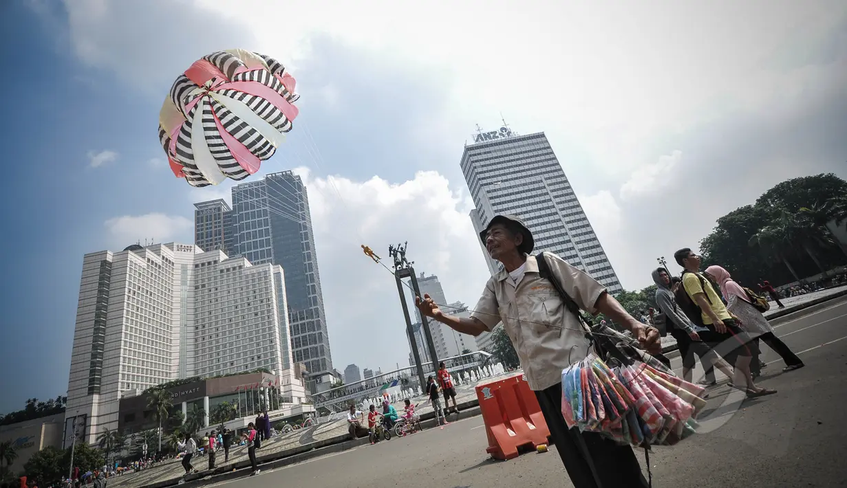 Pedagang parasut mainan saat menerbangkan barang dagangannya di kawasan Bundaran HI, Jakarta, Minggu (22/3/2015).  Seiring dengan perkembangan zaman dan modernisasi, permainan tradisional kini mulai tergantikan. (Liputan6.com/Faizal Fanani)