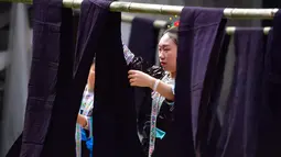 Seorang wanita menjemur kain dalam festival "Liang Bu" yang digelar di Desa Dangjiu di Gandong, Wilayah Otonom Etnis Miao Rongshui, Daerah Otonom Etnis Zhuang Guangxi, China selatan (25/10/2020). Penamaan "Liang Bu" sendiri diberikan karena tampilannya yang berkilau. (Xinhua/Huang Xiaobang)