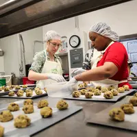 Elizabeth Bennett (kiri), penyelenggara Together We Bake, dan partisipan, Nikki Yates (kanan), terlihat membuat cookies. (Morgan McCloy/NPR)