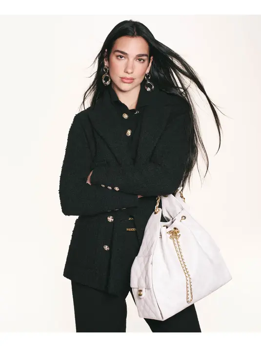 Dua Lipa memancarkan pesona high-fashion khas CHANEL dengan berbagai gaya yang berbeda namun tetap mempertahankan estetika elegan dan modern. Pada salah satu potret, Dua Lipa terlihat mengenakan setelan denim oversized dengan detail sulaman berkilauan yang memberikan efek glamor pada gaya kasualnya. [Dok/CHANEL].