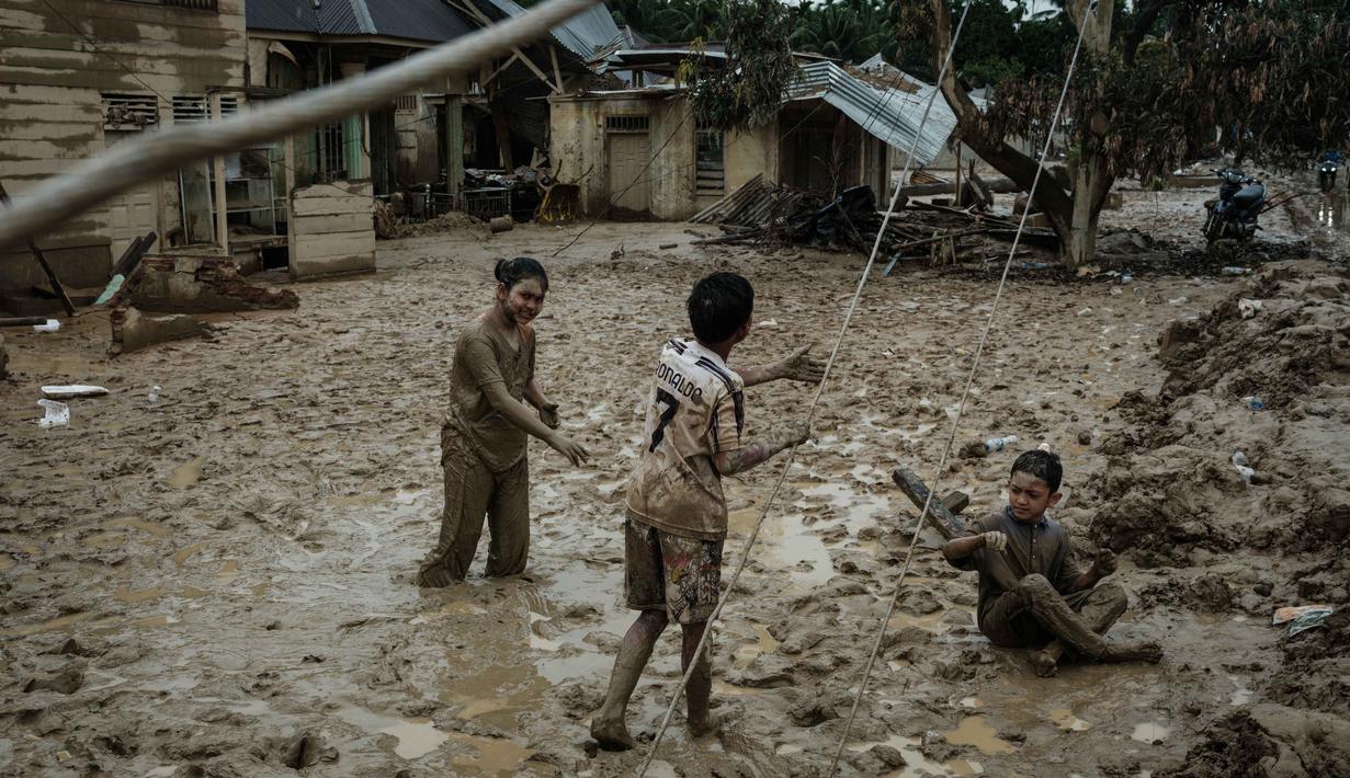 Banjir bandang ini disebut sebagai salah satu yang terbesar dalam beberapa dekade terakhir. Tampak dalam foto, anak-anak bermain di tanah berlumpur di Babo, Aceh Tamiang, pada Senin 15 Desember 2025. (Yasuyoshi CHIBA/AFP)