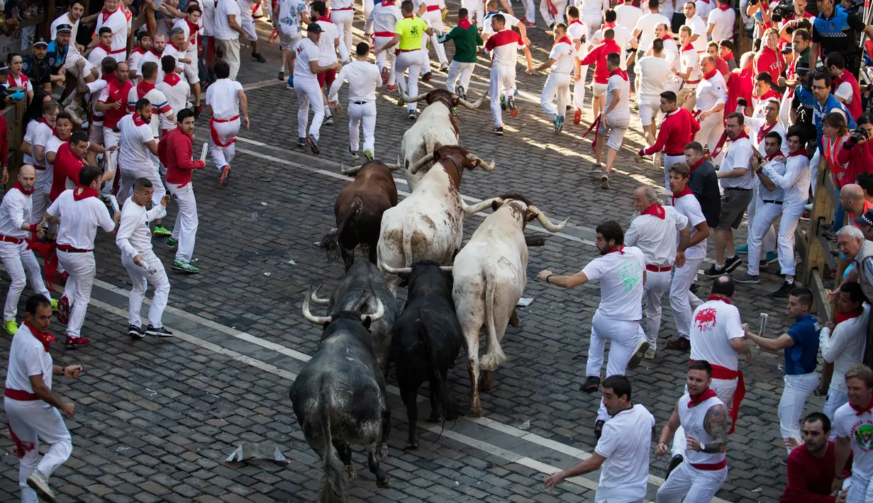 Para peserta menghindar dari kejaran banteng selama Festival San Fermin di Pamplona, Spanyol, Senin (9/7). (JAIME REINA/AFP)