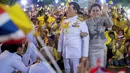 Raja Maha Vajiralongkorn dan Ratu Suthida melambaikan tangan ke pendukungnya di Bangkok, Thailand, Minggu (1/11/2020). Di bawah tekanan yang meningkat dari pengunjuk rasa yang menuntut reformasi pada monarki, Raja dan Ratu Thailand bertemu dengan ribuan pendukungnya. (AP Photo/Wason Wanichakorn)