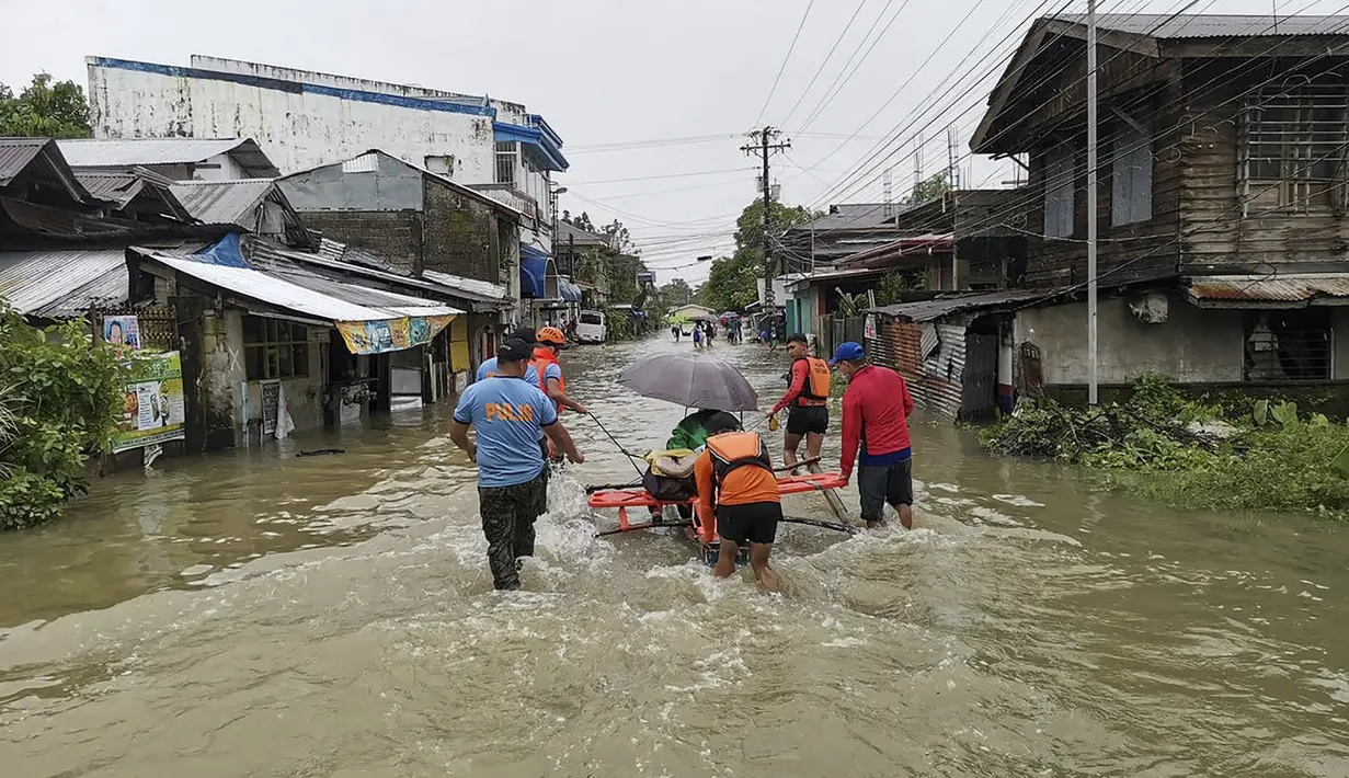 Penjaga pantai dan personel polisi mengevakuasi seorang penduduk dari daerah banjir di Kota Abuyog, Provinsi Leyte, Filipina, 11 April 2022. Banjir terjadi menyusul hujan lebat yang disebabkan oleh badai tropis Agaton. (Philippine Coast Guard (PCG)/AFP)
