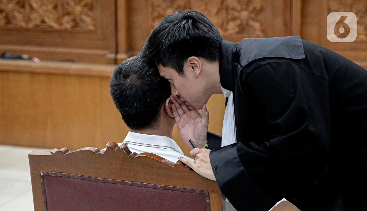 Terdakwa kasus perintangan penyidikan kematian Brigadir J, Irfan Widyanto berdiskusi dengan kuasa hukum jelang sidang perdana di Pengadilan Negeri Jakarta Selatan, Rabu (19/10/2022). Irfan Widyanto didakwa merusak CCTV yang membuat terhalanginya penyidikan kasus pembunuhan Yosua Hutabarat. (Liputan6.com/Faizal Fanani)