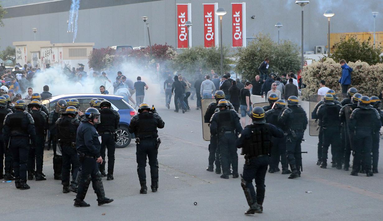 Polisi anti rusuh Prancis menghalau  suporter Bastia dengan gas air mata saat laga SC Bastia melawan Olympic Lyon di Armand Cesari stadium, Bastia, (16/4/2017). Laga ini akhirnya dihentikan LFP. (AFP/Pascal Pochard-Casabianca)