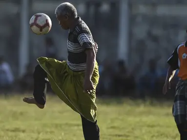 Seorang pria mengenakan sarung berusaha mengontrol bola saat merayakan HUT ke-74 RI di Blang Pidie provinsi Aceh (17/8/2019). Indonesia merayakan kemerdekaan yang ke-74 dari pemerintahan kolonial Belanda. (AFP Photo/Chaideer Mahyuddin)