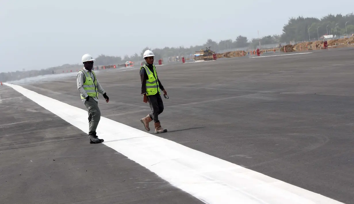 Pekerja melintasi sisi landasan pacu atau runway Bandara Internasional Yogyakarta, Kulon Progo, DI Yogyakarta, Rabu (24/4). Landasan pacu Bandara Internasional Yogyakarta memiliki panjang 3.250 meter dengan lebar 45 meter. (Liputan6.com/Helmi Fithriansyah)