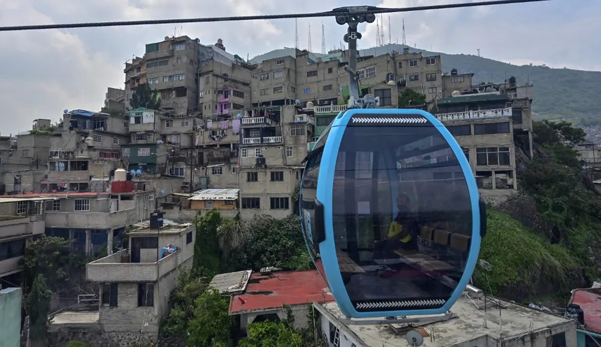 Penumpang melakukan perjalanan dengan sistem kereta gantung yang dijuluki Cablebus setelah peresmiannya di pinggiran Mexico City, Meksiko, 12 Juli 2021. Sistem kereta gantung ini memudahkan penumpang untuk melakukan perjalanan dari Cuautepec menuju pusat kota. (PEDRO PARDO/AFP)
