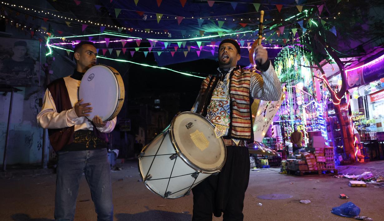 "Musaharatis" Palestina menabuh genderang mereka saat melakukan tur pada malam pertama bulan Ramadan, di Rafah di Jalur Gaza selatan, Kamis (23/3/2023). (Photo by SAID KHATIB / AFP)