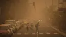 Sejumlah orang menyeberangi jalan saat badai pasir Gurun Sahara menerjang Santa Cruz de Tenerife, Kepulauan Canary, Spanyol, Minggu (23/2/2020). Pemerintah setempat menyarankan penduduk untuk tetap di dalam rumah. (AP Photo/Andres Gutierrez)