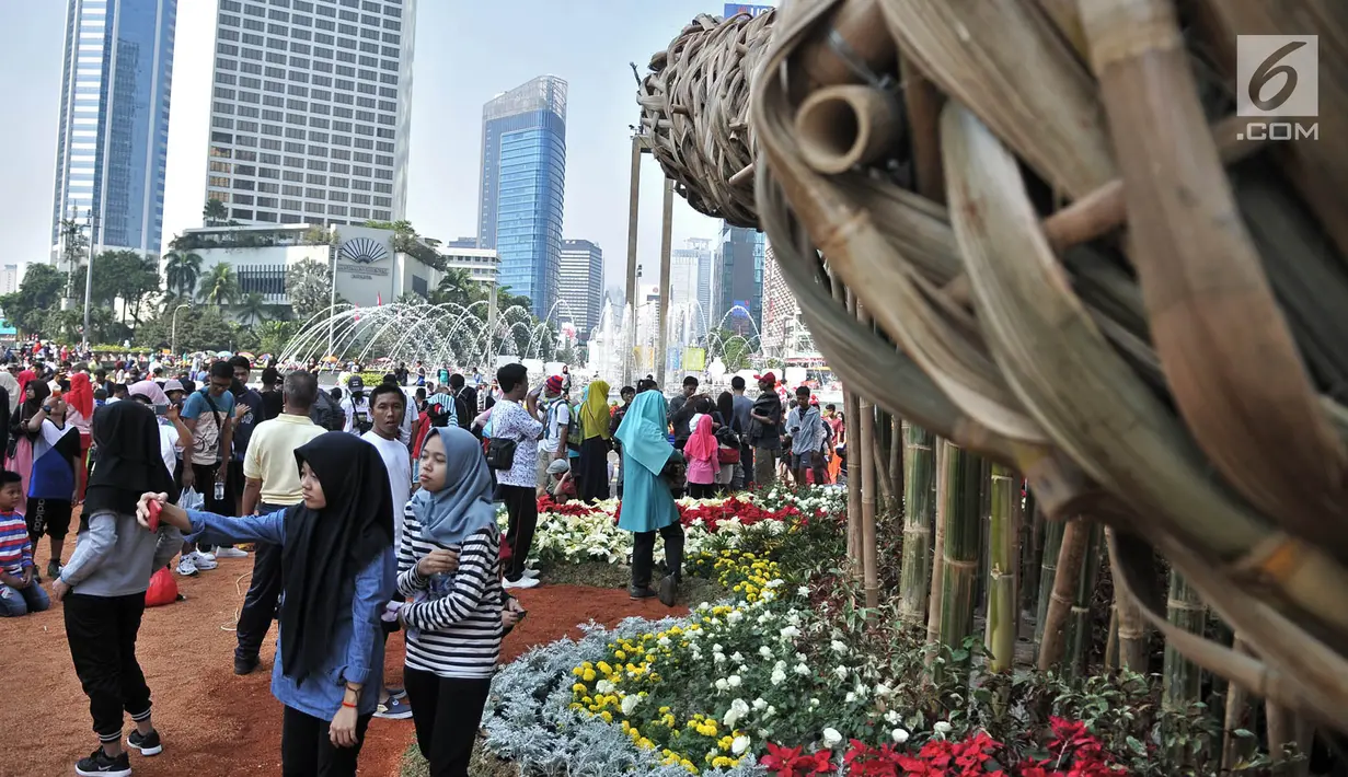 Pengunjung Car Free Day berfoto dekat instalasi bambu "Getih Getah" di Bundaran HI, Jakarta, Minggu (19/8). Dijetahui, nama Getah-getih diberikan sesuai dengan identitas dari bangsa Indonesia sendiri yakni Merah-Putih. (Merdeka.com/ Iqbal S. Nugroho)