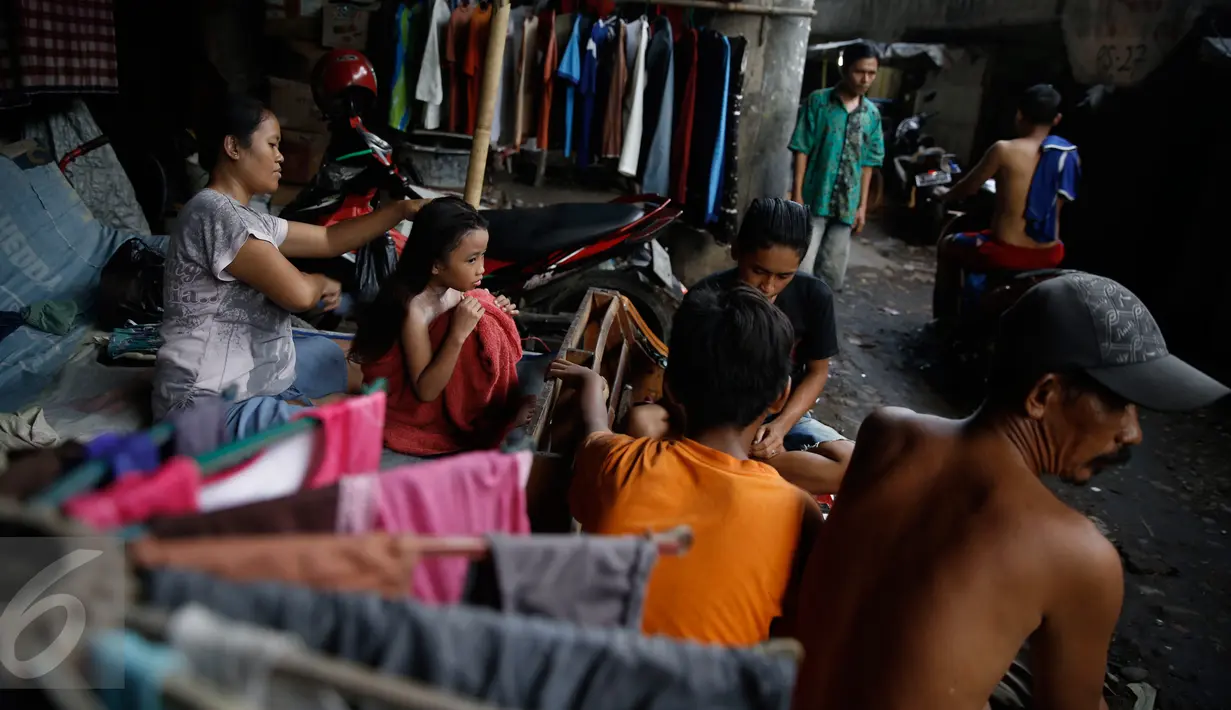 Seorang ibu menyisir rambut anaknya di pemukiman kolong jalan tol Ir Wiyoto Wiyono, Penjaringan, Jakarta, Minggu (13/3). Pemprov DKI berencana menggusur sebanyak delapan Rukun Warga (RW) yang menghuni kolong tol tersebut. (Liputan6.com/Faizal Fanani)
