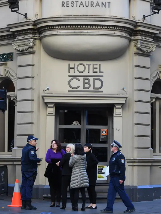 Polisi berbicara dengan warga di luar hotel di tempat kejadian setelah seorang pria menikam seorang wanita dan berusaha menikam orang lain di pusat Sydney (13/8/2019). (AFP Photo/Saeed Khan)