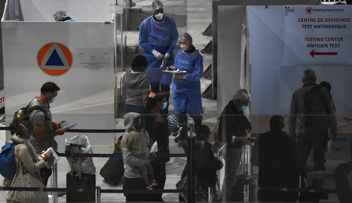 Wisatawan mengantre di pintu masuk pusat pengujian Covid-19 di area kedatangan bandara internasional Roissy Charles-de-Gaulle, Paris, Senin (1/2/2021). Prancis menutup perbatasannya untuk mayoritas negara non-Uni Eropa akibat  situasi pandemi Covid-19. (Christophe ARCHAMBAULT/AFP)