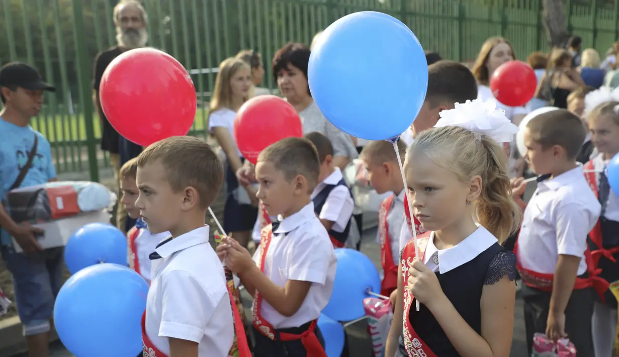 Anak-anak kelas satu mengikuti upacara yang menandai dimulainya kelas di sebuah sekolah di Mariupol, daerah yang dikuasai oleh pasukan separatis yang didukung Rusia, Ukraina timur, Kamis (1/9/2022). Banyak sekolah Ukraina dibuka kembali pada 1 September untuk pertama kalinya sejak invasi Rusia dimulai pada 24 Februari lalu. (AP Photo)