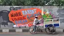 Para pengguna jalan melintasi mural Tolak RUU Pilkada di tembok fly over kawasan Pejompongan, Jakarta, (28/9/14). (Liputan6.com/Miftahul Hayat) 