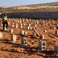 Seorang pria berjalan melewati makam korban banjir bandang di Derna, Libya, Jumat (15/9/2023). Jumlah korban tewas di kota pesisir Derna telah melonjak hingga lebih dari 10 ribu orang ketika upaya pencarian terus dilakukan menyusul banjir besar yang diakibatkan oleh jebolnya dua bendungan saat hujan lebat, kata Bulan Sabit Merah Libya pada Kamis. (AP Photo/Yousef Murad)