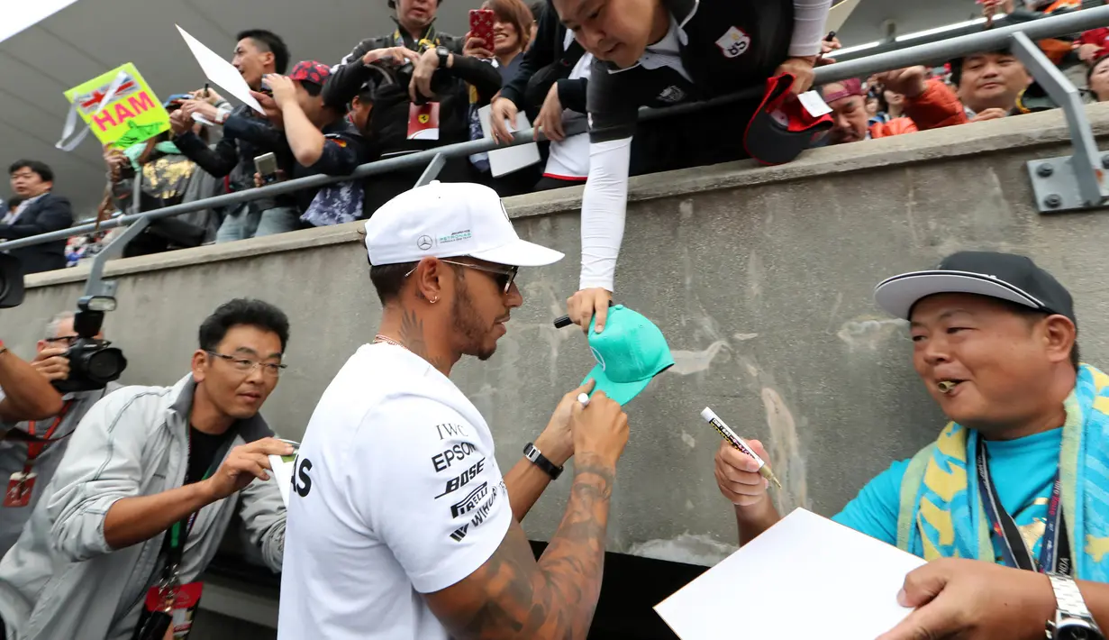 Pembalap Mercedes Lewis Hamilton memberi tanda tangan disebuah topi penggemarnya jelang Grand Prix F1 di Sirkuit Suzuka, Jepang (5/10). F1 GP Jepang akan digelar pada tanggal 8 Oktober mendatang. (AP Photo/Eugene Hoshiko)