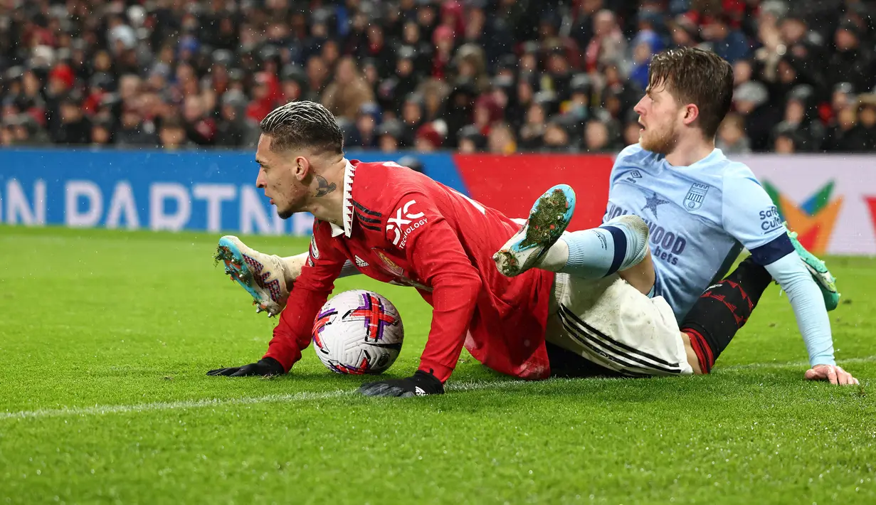 Gelandang Manchester United, Antony (kiri) dan gelandang Brentford, Mathias Jensen terjatuh saat perebutan bola pada laga lanjutan Liga Inggris 2022/2023 di Old Trafford Stadium, Manchester, Kamis (6/4/2023) dini hari WIB. (AFP/Darren Staples