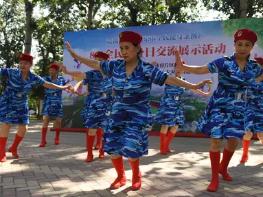Para wanita lansia melakukan tarian dengan mengenakan pakaian bergaya militer saat mengikuti Hari Kebugaran Nasional di Beijing, Tiongkok (8/8). Hari tersebut juga bertepetan dengan hari pembukaan Olimpiade Beijing 2008. (AFP Photo/Greg Baker)