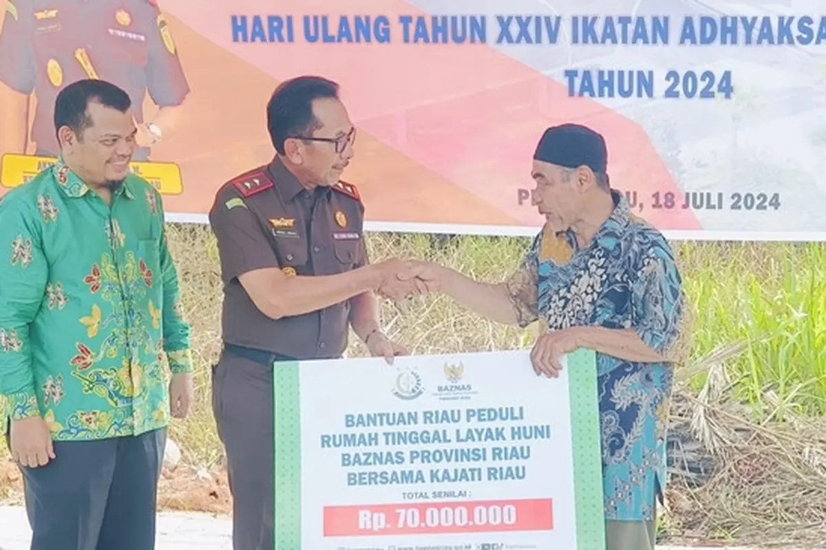 Kepala Kejati Riau Akmal Abbas menyerahkan bantuan pembuatan rumah kepada cleaning service sebagai rangkaian Hari Bhkati Adhyaksa.
