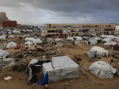Sebuah foto menunjukkan tenda-tenda penampungan keluarga-keluarga Palestina yang mengungsi, didirikan di sepanjang pantai Kota Gaza saat angin musim dingin yang kencang menerpa wilayah tersebut pada Selasa 13 Januari 2026. Musim dingin menjadi ancaman nyata bagi para pengungsi Palestina di Jalur Gaza. (Omar AL-QATTAA/AFP)