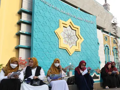Umat Islam membaca Al-Quran sambil menunggu waktu berbuka puasa di halaman Masjid Raya Jakarta Islamic Center, Jakarta Utara, Senin (18/4/2022). Acara ngabuburit sambil khataman Al-Quran ini merupakan rangkaian acara menyambut 17 Ramadhan atau malam Nuzulul Quran. (Liputan6.com/Herman Zakharia)