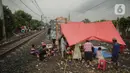 Pengungsi banjir mendirikan tenda di jalur rel kereta commuterline Tangerang-Duri di Kembangan Baru, Jakarta, Jumat (3/1/2020). Jalur rel yang nonaktif sementara karena banjir dimanfaatkan warga sekitar untuk mendirikan tenda darurat karena rumah mereka masih terendam. (Liputan6.com/Faizal Fanani)