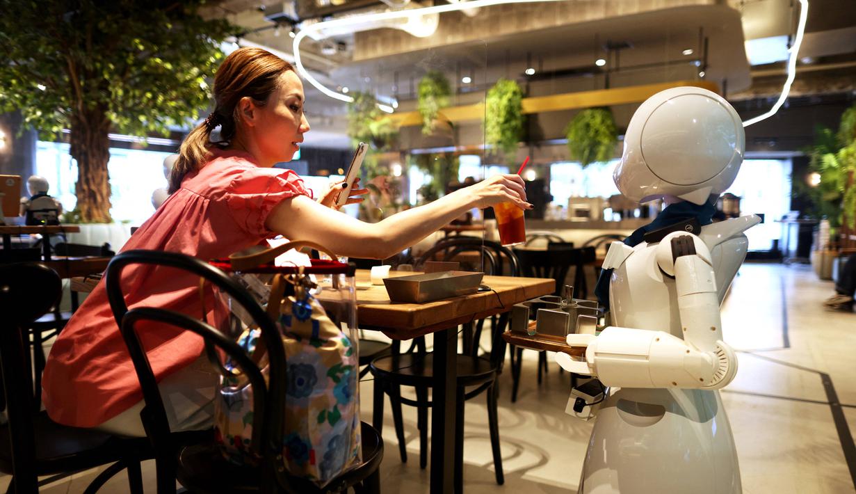 Robot humanoid mengantarkan minuman kepada pelanggan di Dawn Cafe, Tokyo, Jepang, 17 Agustus 2021. Peluncuran kafe ini bersamaan dengan Paralimpiade yang akan dibuka pada 24 Agustus. (Behrouz MEHRI/AFP)