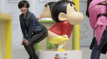 Seorang wanita berpose mengikuti gaya Crayon Shinchan saat berfoto di pameran Joy City, Beijing (5/5/2015). Lima puluh model karakter kartun Jepang dalam berbagai pose dan ekspresi dihadirkan dipameran tersebut. (REUTERS/Jason Lee)