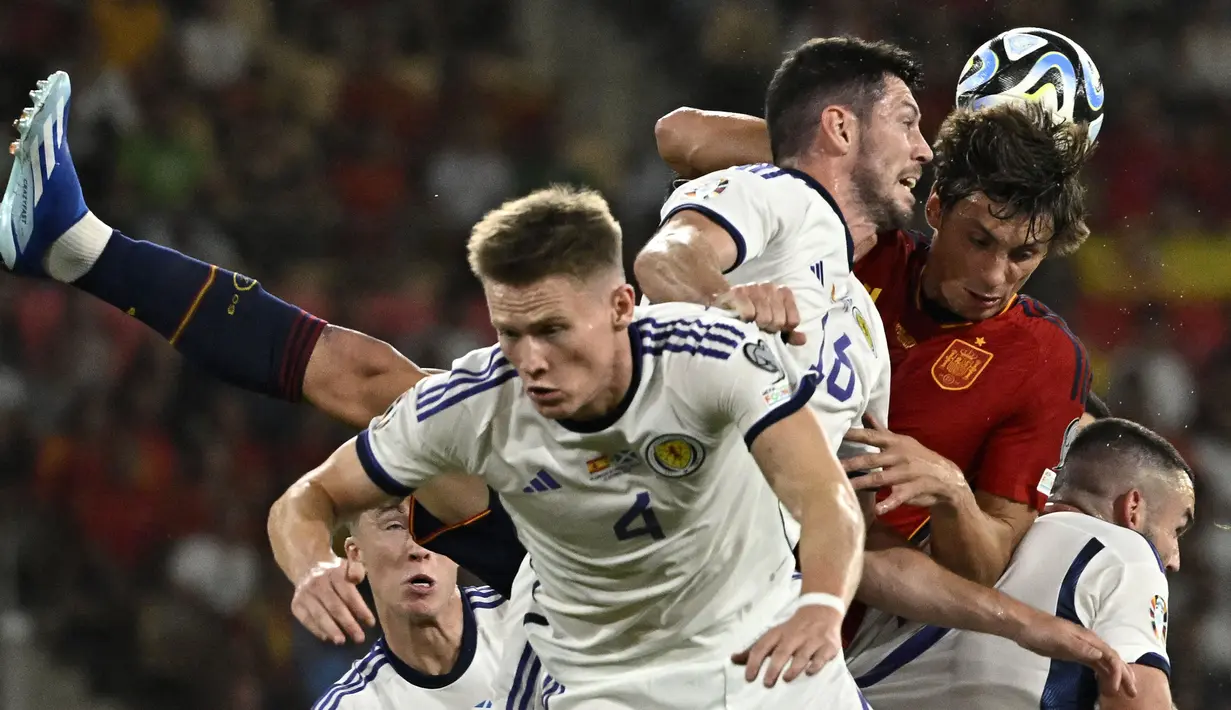 Pemain Spanyol, Robin Le Normand (kanan) berduel udara dengan pemain Skotlandia, Scott McKenna (tengah) pada laga Grup A Kualifikasi Euro 2024 di La Cartuja Stadium, Sevilla, Spanyol, Jumat (13/10/2023) dini hari WIB. (AFP/Javier Soriano)