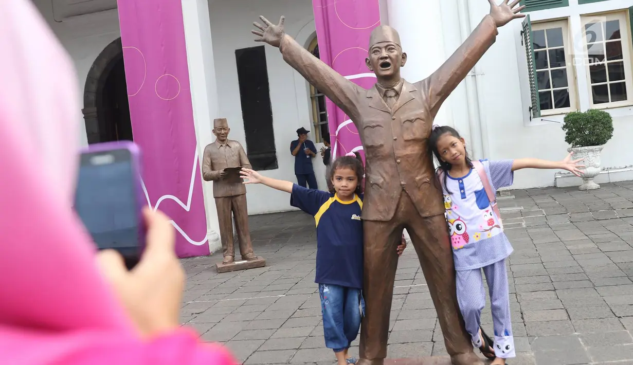 Dua anak berfoto dengan patung Presiden pertama RI Sukarno dipajang di depan Museum Fatahillah, kawasan Kota Tua, Jakarta, Rabu (15/11). Patung karya seniman Dolorosa Sinaga itu dibuat dengan bahan Resin. (Liputan6.com/Immanuel Antonius)