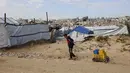 Dalam tugasnya, NCAG akan bertanggung jawab kepada Dewan Perdamaian Gaza. Tampak dalam foto, seorang anak laki-laki Palestina yang mengungsi dan hidup di antara reruntuhan rumah dan bangunan yang hancur akibat serangan militer Israel selama lebih dari dua tahun di wilayah Gaza, menyeret kontainer berisi air di kamp pengungsi Jabalia, di bagian utara Jalur Gaza pada Sabtu 17 Januari 2026. (Omar AL-QATTAA/AFP)
