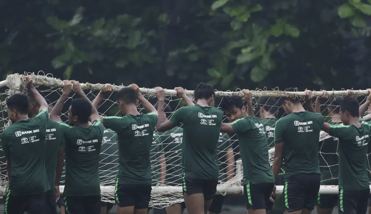 Para pemain Timnas Indonesia U-22 gotong royong mengangkat gawang usai latihan di Lapangan ABC, Jakarta, Senin (14/1). Latihan ini merupakan persiapan jelang Piala AFF U-22. (Bola.com/Vitalis Yogi Trisna)