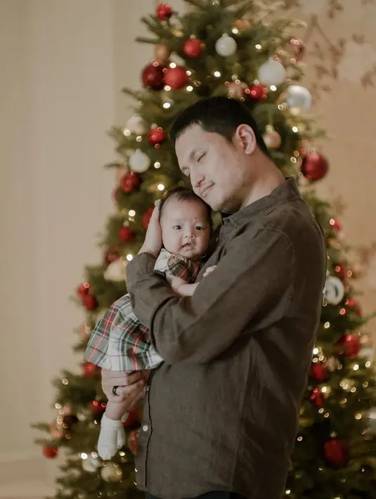 Sang putri kenakan mini dress kotak-kotak dan kaus kaki. Dipeluk sang ayah yang kenakan kemeja cokelat lengan panjang [@jessicatanoe]