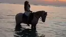 Saat mengenakan pakaian putih tersebut, Fuji pun berpose sambil menaiki kuda di pinggir pantai. Tampak rambutnya pun tergerai. [@fuji_an]
