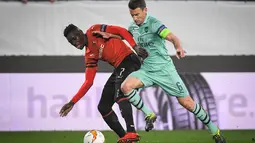 Duel Koscielny dengan Ismaila Sarr pada leg 1, babak 16 besar Liga Europa yang berlangsung di Stadion Roazhon Park, Rennes, Jumat (8/3). Arsenal kalah 1-3 kontra Rennes. (AFP/Damien Meyer)