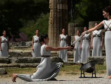 Aktris Yunani, Katerina Lechou, memberikan api olimpiade yang baru saja dinyalakan dalam suatu upacara di Candi Hera yang terletak di bekas kota tua Olympia, Yunani, Kamis (21/4/2016). (AFP/Aris Messinis)