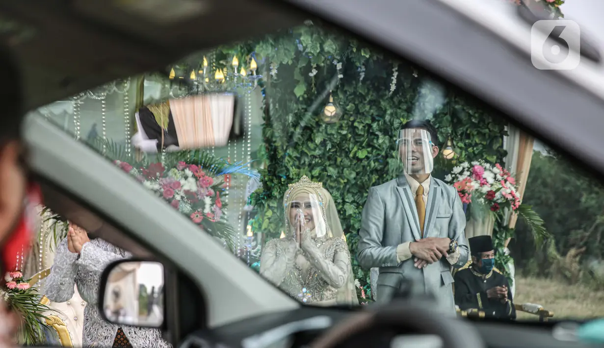 Pasangan mempelai saat menyapa tamu undangan pada acara resepsi pernikahan secara "drive thru" di Bekasi, Jawa Barat, Sabtu (8/8/2020). Resepsi pernikahan secara drive thru menjadi alternatif pesta pernikahan guna mencegah penyebaran wabah COVID-19. (Liputan6.com/Faizal Fanani)