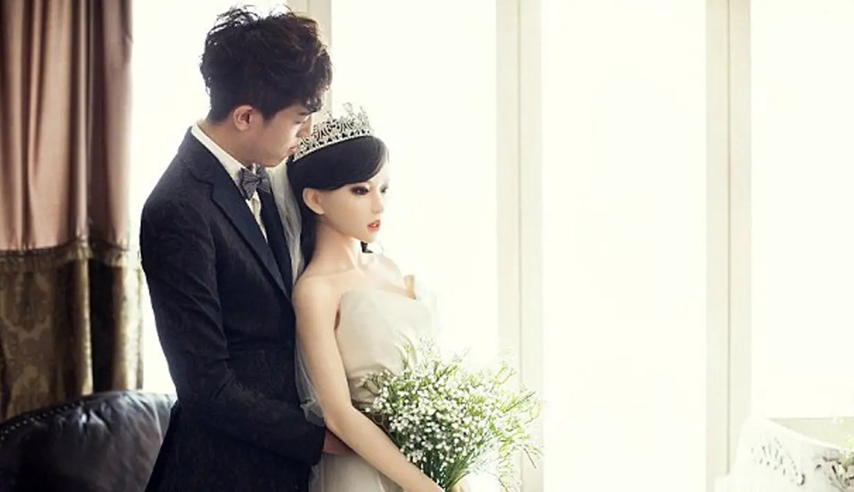 Seorang pria asal Beijing, China bersama boneka seks, yang menjadi mempelai wanita, saat melakukan sesi foto pada pesta pernikahan mereka. Pria 28 tahun yang tidak disebutkan namanya itu divonis mengidap penyakit kanker mematikan. (dailymail.co.uk)