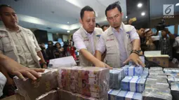 Petugas menata barang bukti hasil tindak pidana pencucian uang (TPPU) kasus narkoba di kantor BNN, Jakarta, Selasa (13/6). Total senilai Rp 39 miliar disita dari empat tersangka yang terkait dengan jaringan Freddy Budiman. (Liputan6.com/Yoppy Renato)